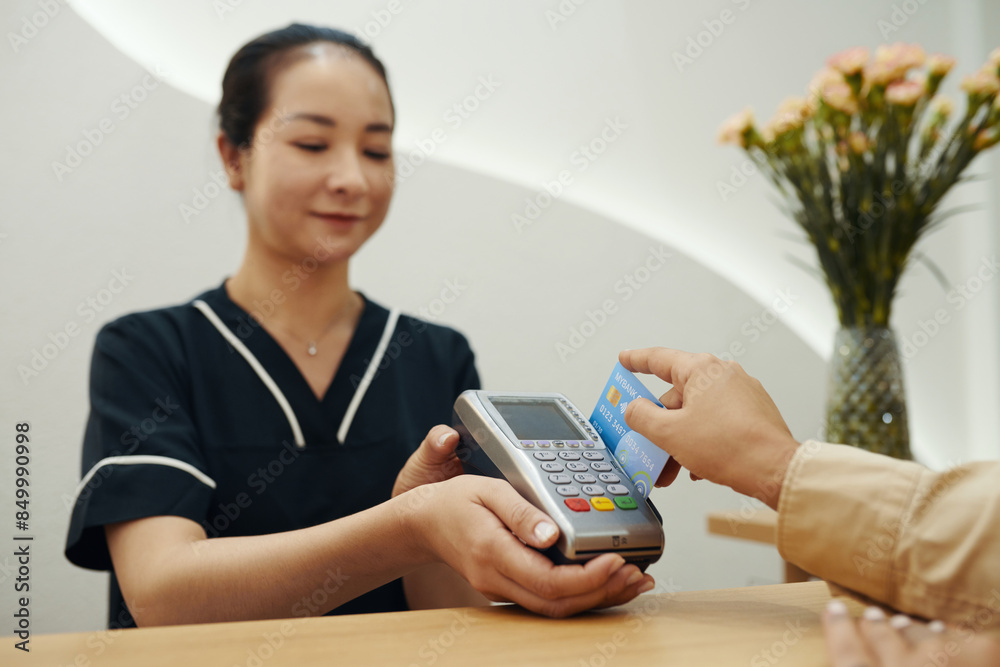 Client swiping credit car when paying for service in beauty salon Client swiping credit car when paying for service in beauty salon