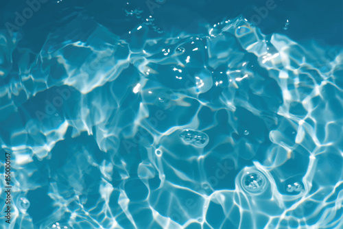 Blue water with ripples on the surface. Defocus blurred transparent blue colored clear calm water surface texture with splashes and bubbles. Water waves with shining pattern texture background.