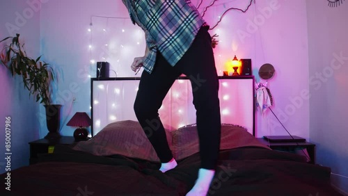 Guy dances, standing right on the bed, and makes a fool of himself in his room at night.