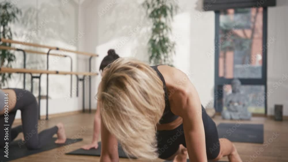 Close camera view of pretty Caucasian woman with short hair completing stretching exercise. Working on health of her body with group of other people. Doing yoga with friends. Close camera view of pretty Caucasian woman with short hair completing stretching exercise. Working on health of her body with group of other people. Doing yoga with friends.