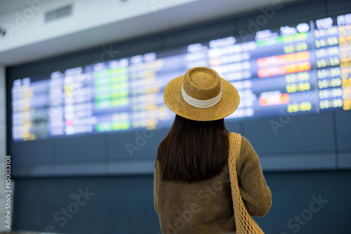 Tourist woman look at the travel schedule of the flight in the airport
