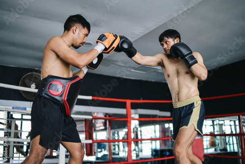 Pottrait Of Asian Fighter Man Excercising Punch Wearing Pads Gloves On Boxing Ring photo