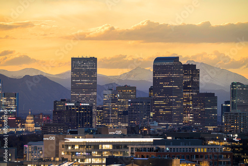 Telephoto view of the Denver skyline glowing at sunset with mountains behind