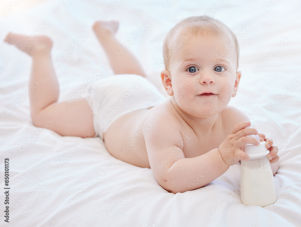 Baby, portrait and playing on bed with bottle for milk nutrition, child development and healthy bones in home. Boy infant, newborn and liquid calcium for food with growth, wellness and morning peace Baby, portrait and playing on bed with bottle for milk nutrition, child development and healthy bones in home. Boy infant, newborn and liquid calcium for food with growth, wellness and morning peace