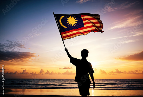 man holding malaysia flag on beach at sunset