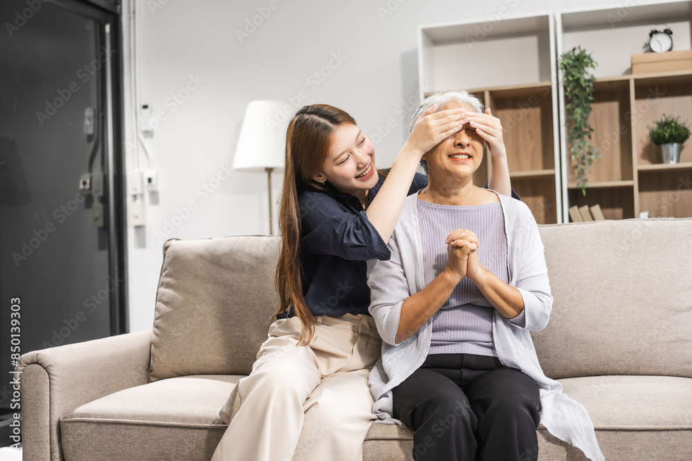A mature mom and her young daughter, both Asian, sit on sofa, celebrating Mother's Day. They share comfort, closeness, warmth, embracing their bond with tenderness, laughter, and cherished memories. A mature mom and her young daughter, both Asian, sit on sofa, celebrating Mother's Day. They share comfort, closeness, warmth, embracing their bond with tenderness, laughter, and cherished memories.