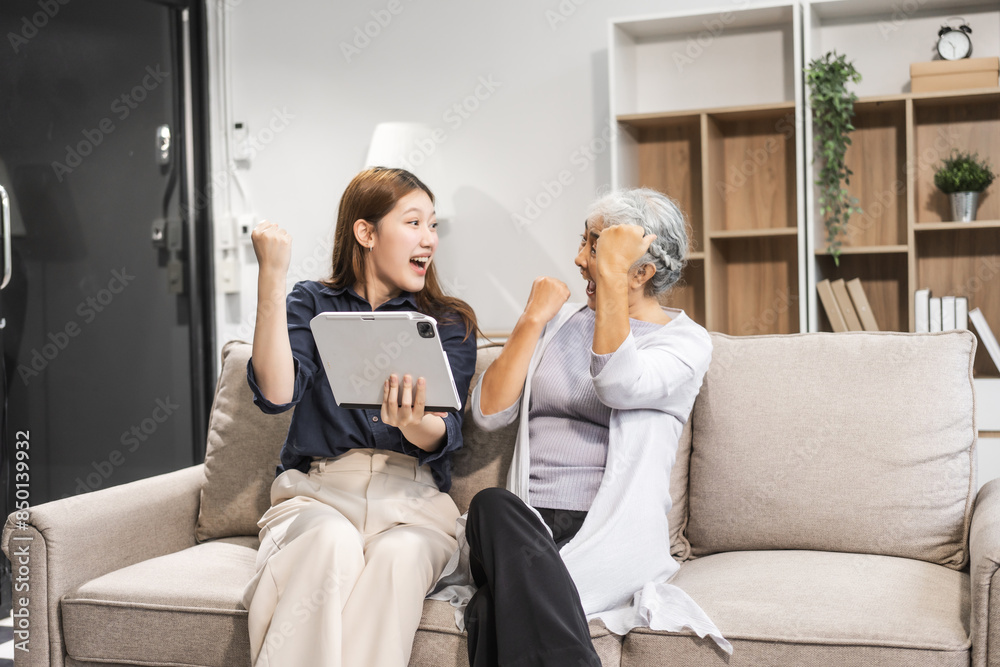 A mature mom and her young daughter, both Asian, sit on sofa, celebrating Mother's Day. They share comfort, closeness, warmth, embracing their bond with tenderness, laughter, and cherished memories. A mature mom and her young daughter, both Asian, sit on sofa, celebrating Mother's Day. They share comfort, closeness, warmth, embracing their bond with tenderness, laughter, and cherished memories.