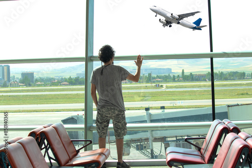Obraz na plátně Passenger waving to the departing plane in the airport waiting room