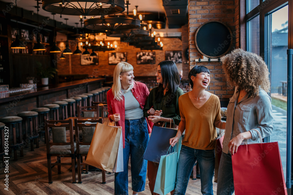 Fototapeta premium A group of diverse female friends walking into a restaurant, chatting happily with shopping bags in hand