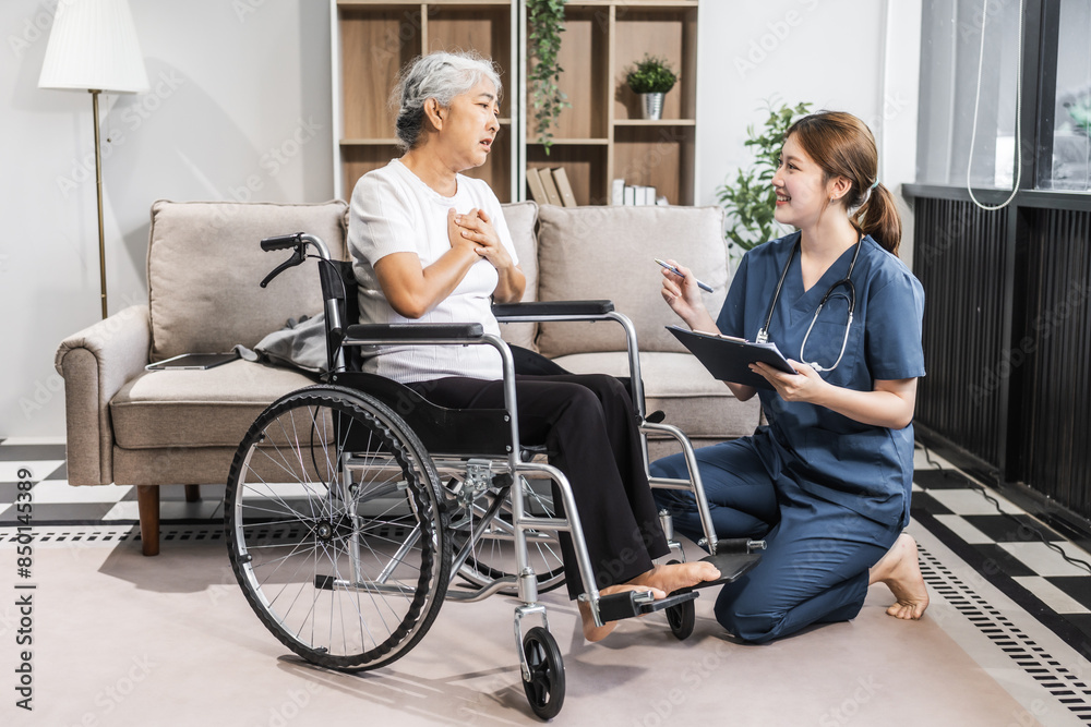 A young female nurse of Asian descent assists an elderly woman in a wheelchair, sitting on a sofa. A young female nurse of Asian descent assists an elderly woman in a wheelchair, sitting on a sofa.