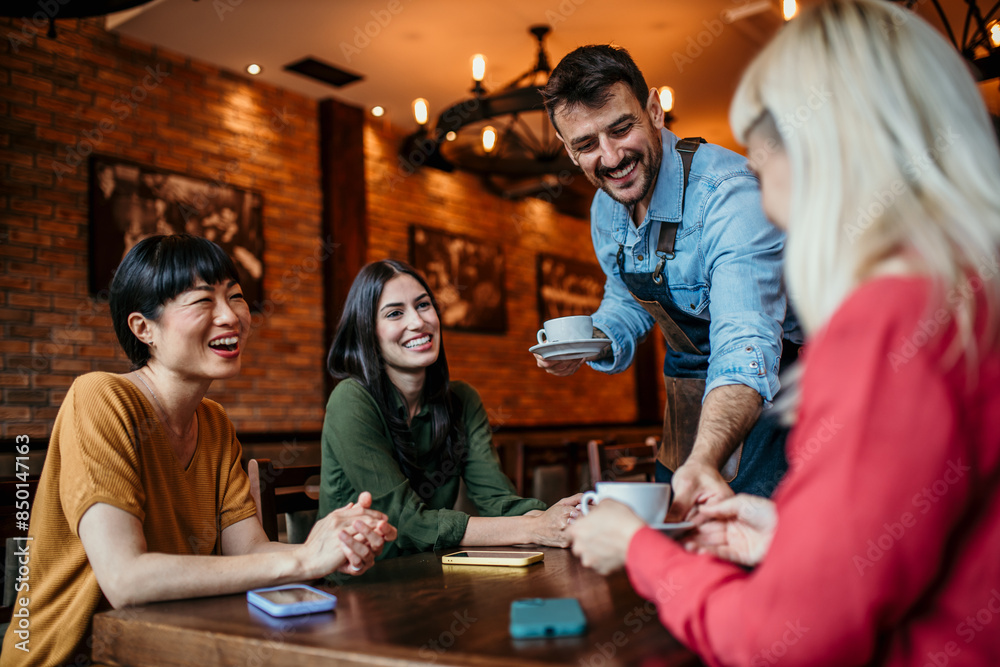 Image of a waiter delivering drinks to a group of females at a restaurant Image of a waiter delivering drinks to a group of females at a restaurant