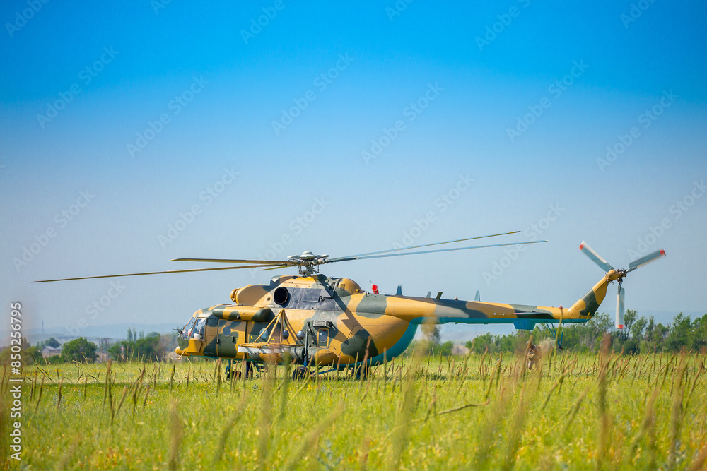 Fototapeta premium In the field is a military helicopter with soldiers. Armed conflict, fighting. Air armament and defense of the territory.