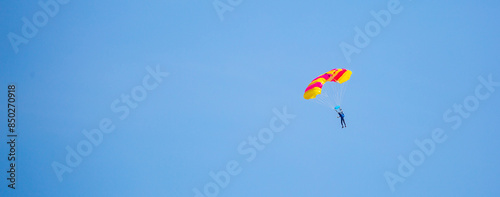 Skydiving. Flying parachutists against the background of the blue sky and mountains. Extreme sport and entertainment.