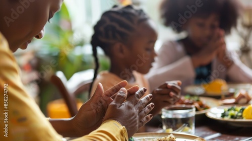 An intergenerational African-American family holds hands and prays before eating a Thanksgiving meal. photo