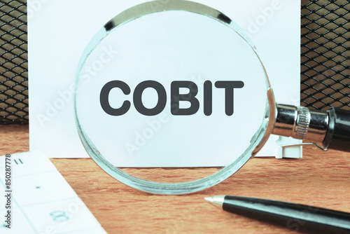 Control Objectives for Information and Related Technologies. COBIT through a magnifying glass on a white sheet photo