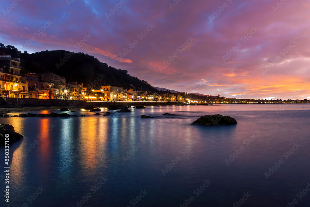 evening or night landscape of evening town coastline in golden lights and sea gulf with calm water and nice reflections with beautisul sunset sky on background evening or night landscape of evening town coastline in golden lights and sea gulf with calm water and nice reflections with beautisul sunset sky on background