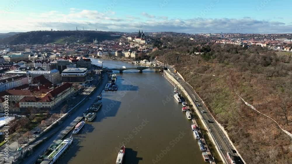Prague, Czechia, December 2022. Drone pushes towards the Svatopluk Čech Bridge above the Vltava river looking west with Petrin Hill and Prague Castle in the distance.