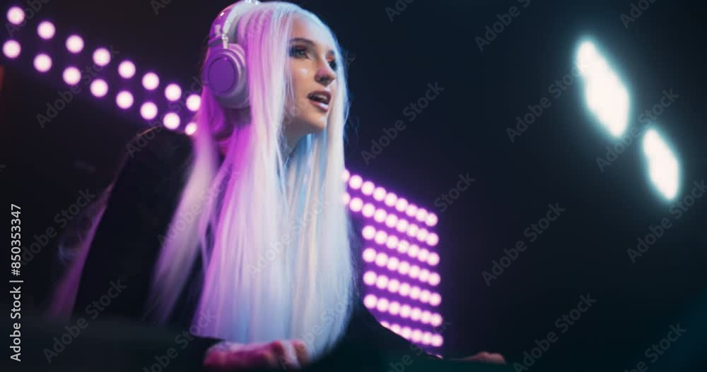 Beautiful DJ Girl Energetically Performing at Nightclub with a Colorful Animated LED Screen Behind Her. Pop Idol Creating a Unique Show Experience with Dynamic Visuals and Powerful EDM Music