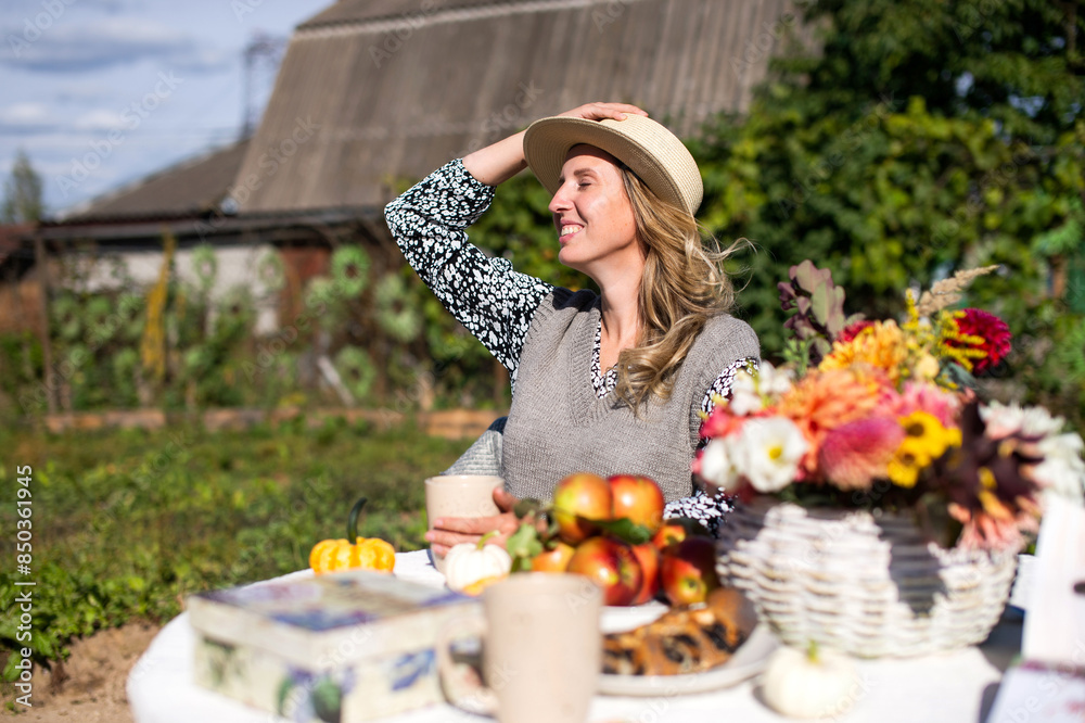 Fototapeta premium A happy girl in a straw hat is sitting on a picnic