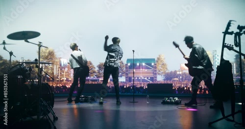 Indie Rock Band Delivers a Mesmerizing Live Performance With Guitars and Drums at a Massive Open Air Concert. Colorful Lights and Powerful Sound Play at a Rock Festival. Footage From the Back