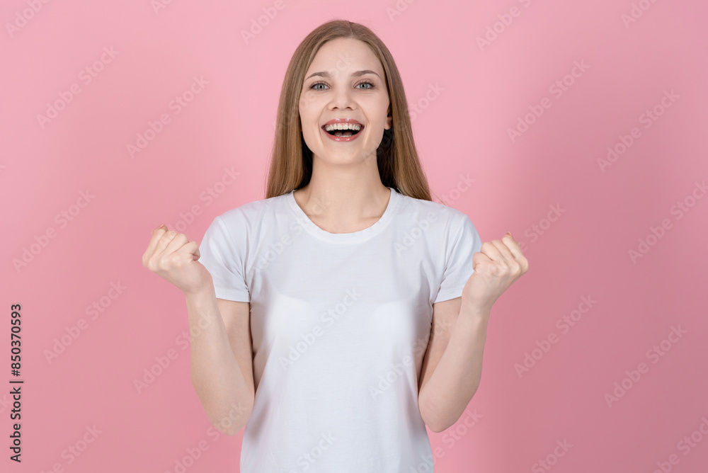 Attractive caucasian young blonde woman in casual white t-shirt looking at camera, smiling happily and showing winner gesture isolated on pink studio background. Success, victory. Attractive caucasian young blonde woman in casual white t-shirt looking at camera, smiling happily and showing winner gesture isolated on pink studio background. Success, victory.