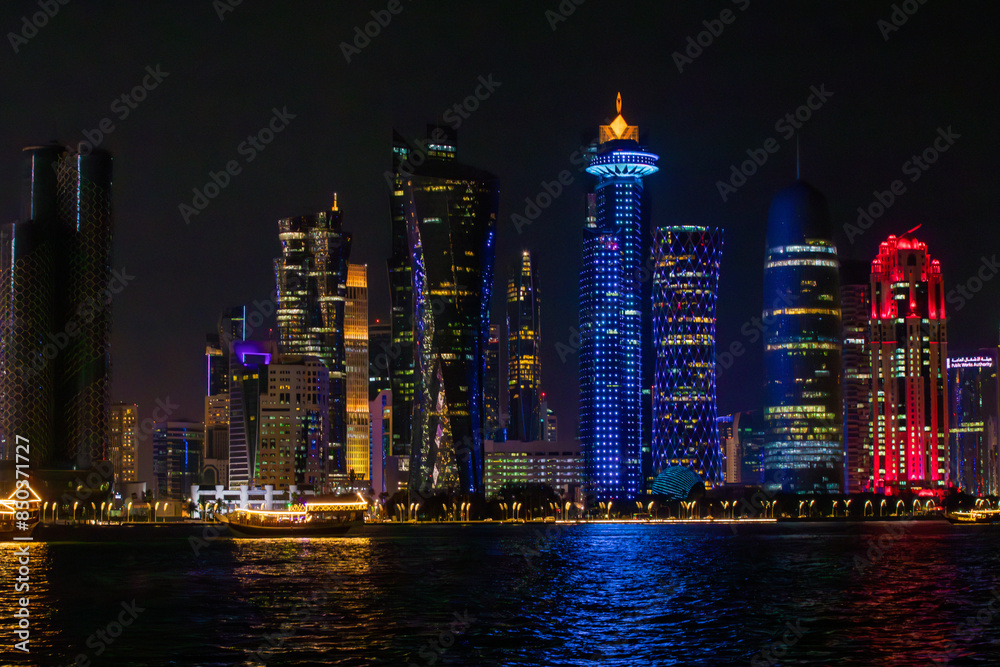 Obraz premium The city skyline is illuminated at night, featuring a boat in the foreground