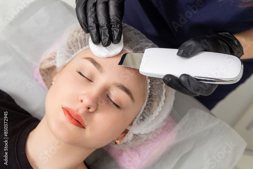 Young woman getting ultrasonic peel skin with skin scrubber.