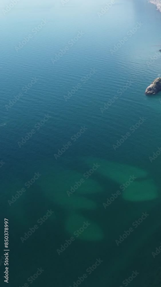 Aerial vertical view of seascape with crystal clear calm azure sea and rocky shores. A beautiful lagoon on backdrop of volcanic rocks. The concept of an ideal destination for summer travel and Aerial vertical view of seascape with crystal clear calm azure sea and rocky shores. A beautiful lagoon on backdrop of volcanic rocks. The concept of an ideal destination for summer travel and