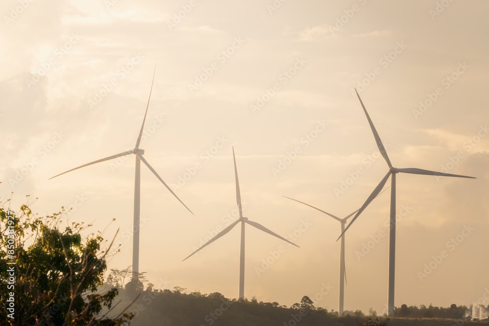 Wind turbines on a hillside against an orange sky at sunset, evoking a serene and peaceful atmosphere. Ideal for promoting renewable energy and environmental sustainability. Wind turbines on a hillside against an orange sky at sunset, evoking a serene and peaceful atmosphere. Ideal for promoting renewable energy and environmental sustainability.