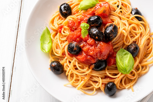 Piatto di spaghetti conditi con pomodoro, olive nere, basilico e olio extravergine di oliva, pasta italiana vegetariana, dieta mediterranea   photo