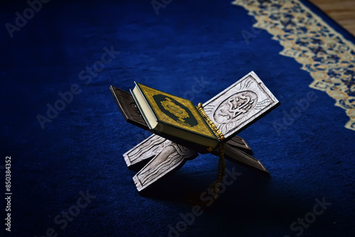 Holy book Quran with prayer beads on carpet photo