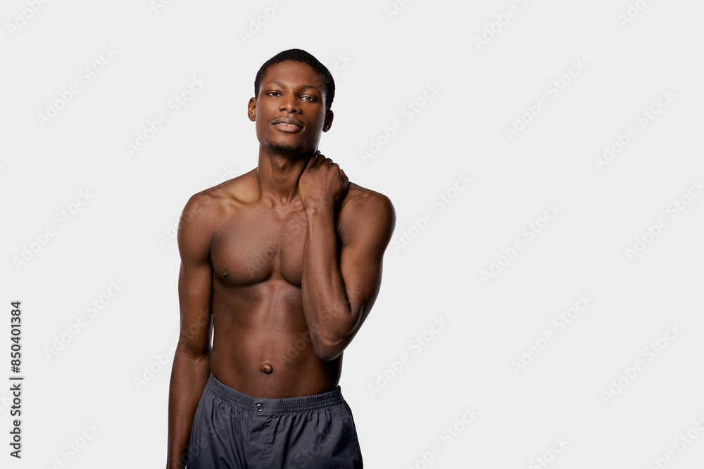 Strong African American man striking a confident pose in a studio with a white background during a beauty routine. Strong African American man striking a confident pose in a studio with a white background during a beauty routine.