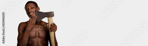 A shirtless African American man holds a large axe in his right hand against a white studio backdrop. photo