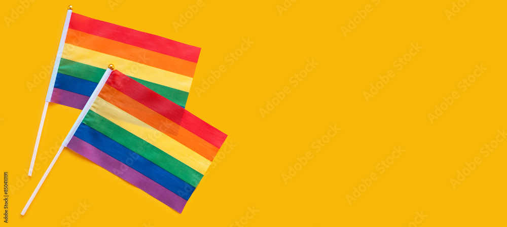 LGBT rainbow flag flat lay on yellow color background. gay marriage, human rights, june parade, lgbtq proud history month concept, coming out day. top view, place for text or logo LGBT rainbow flag flat lay on yellow color background. gay marriage, human rights, june parade, lgbtq proud history month concept, coming out day. top view, place for text or logo