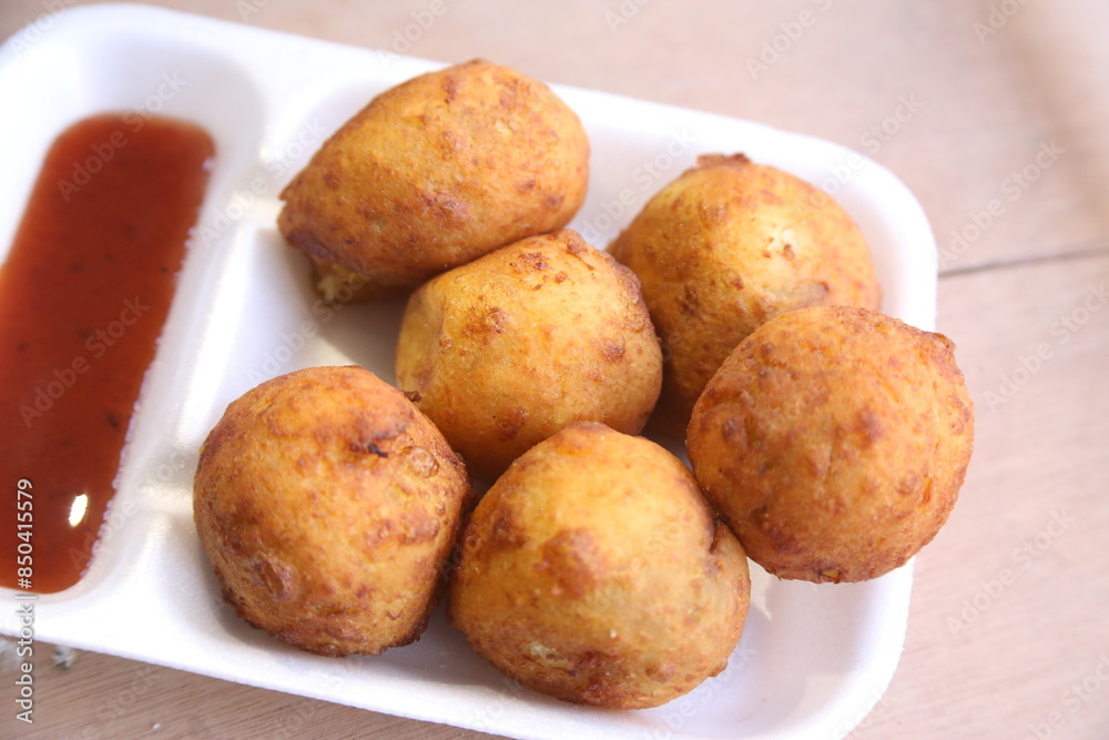 Batata vada or Aloo bonda is tasty,spicy and popular streetfood of India,Maharashtra,served with red chutney / sauce. selective focus Batata vada or Aloo bonda is tasty,spicy and popular streetfood of India,Maharashtra,served with red chutney / sauce. selective focus