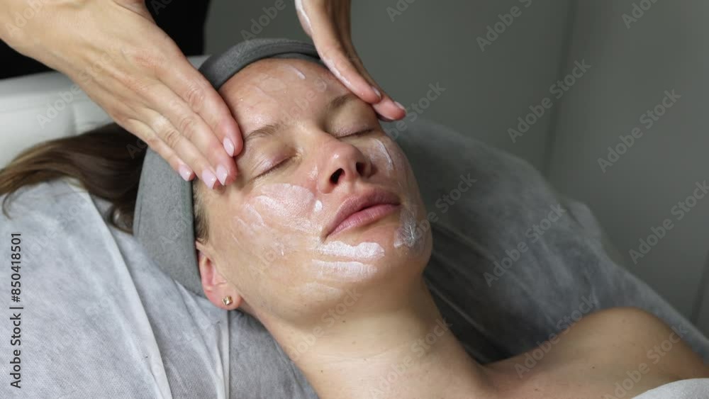 Middle aged female receiving facial massage in beauty salon. Anti aged massage and skincare concept with a beautiful woman. Hands of cosmetology specialist making facial lifting massage in SPA salon Middle aged female receiving facial massage in beauty salon. Anti aged massage and skincare concept with a beautiful woman. Hands of cosmetology specialist making facial lifting massage in SPA salon
