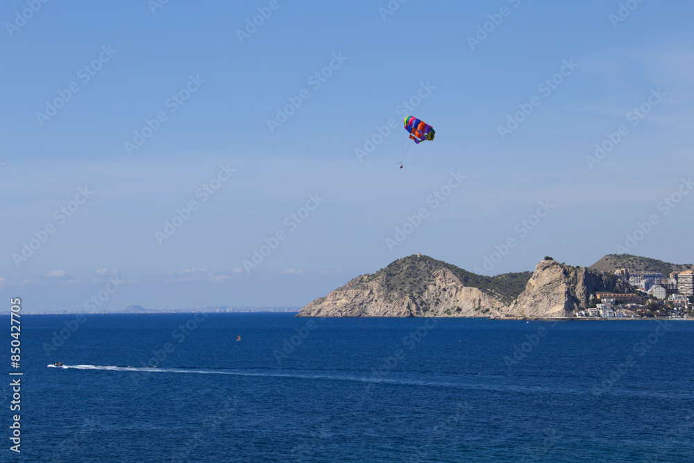 People parascending on Benidorm beach under blue sky People parascending on Benidorm beach under blue sky