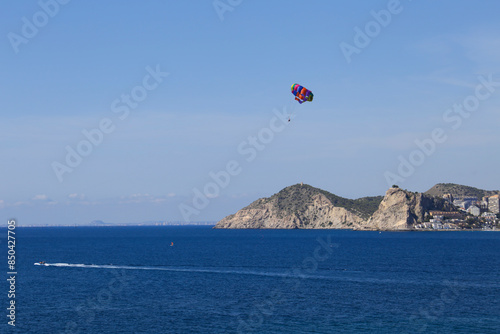 People parascending on Benidorm beach under blue sky