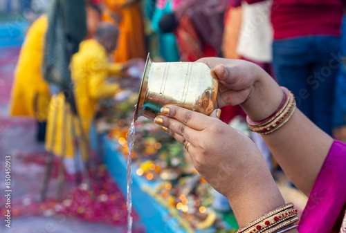holy water offerings by indian devotee doing traditional rituals at chhath festival at morning photo