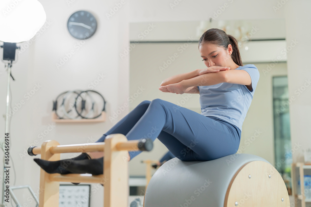 Female pilates trainer working out on pilates machine in studio Young woman stretching and pilates instructor holding her gently Pilates instructor helping a student with exercises class Female pilates trainer working out on pilates machine in studio Young woman stretching and pilates instructor holding her gently Pilates instructor helping a student with exercises class