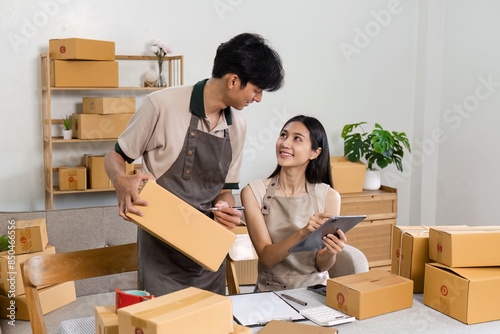 Young entrepreneur Managing Online order in a Small Business Office with Cardboard Boxes and Digital Tablet © itchaznong