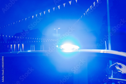 Wallpaper Mural Nighttime police operation with blue lights at an intersection decorated with green and white pennants and a person knocking on the window of the police car Torontodigital.ca