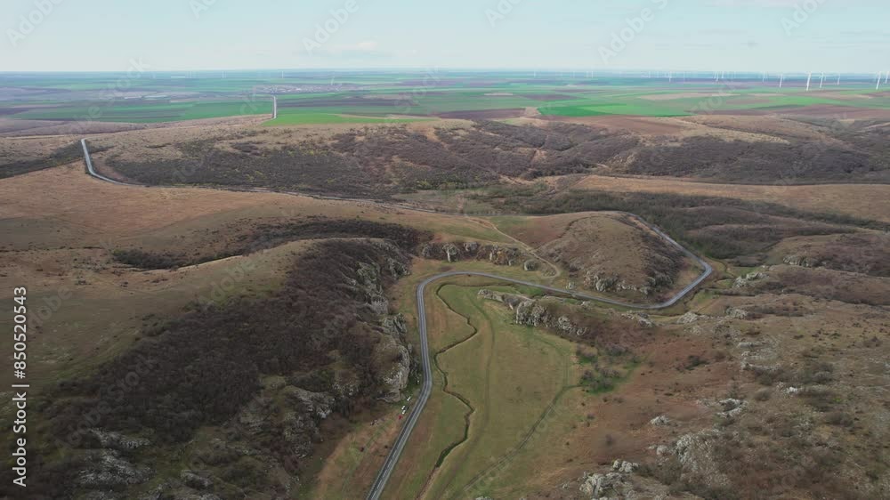 Winding road through Dobrogea Gorges surrounded by rolling hills and vast open landscape Winding road through Dobrogea Gorges surrounded by rolling hills and vast open landscape