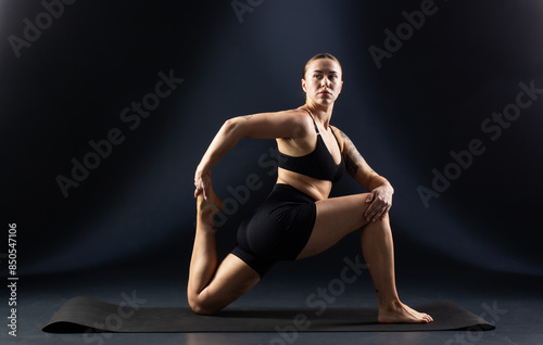 A woman is doing a stretching exercise on a yoga mat