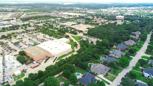 Downtown Southlake Texas mixed use development with large shopping center busy parking lot, residential neighborhood upscale houses swimming pool, municipal area with water tower, aerial view photo