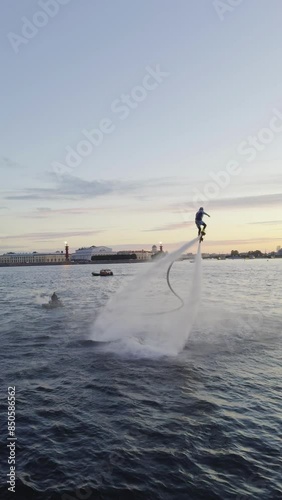 Thrilling flyboarder performing an aerial stunt above the water in Saint Petersburg, Russia. Captivating action shot perfect for extreme sports and adventure themes, highlighting the excitement and photo