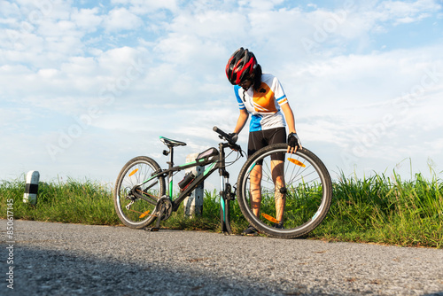 Man cyclist repairing a bike against the background of sky