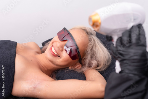 A young asian woman smiles and enjoying a small chitchat before undergoing a Diode ICE laser hair removal procedure for her underarms. photo
