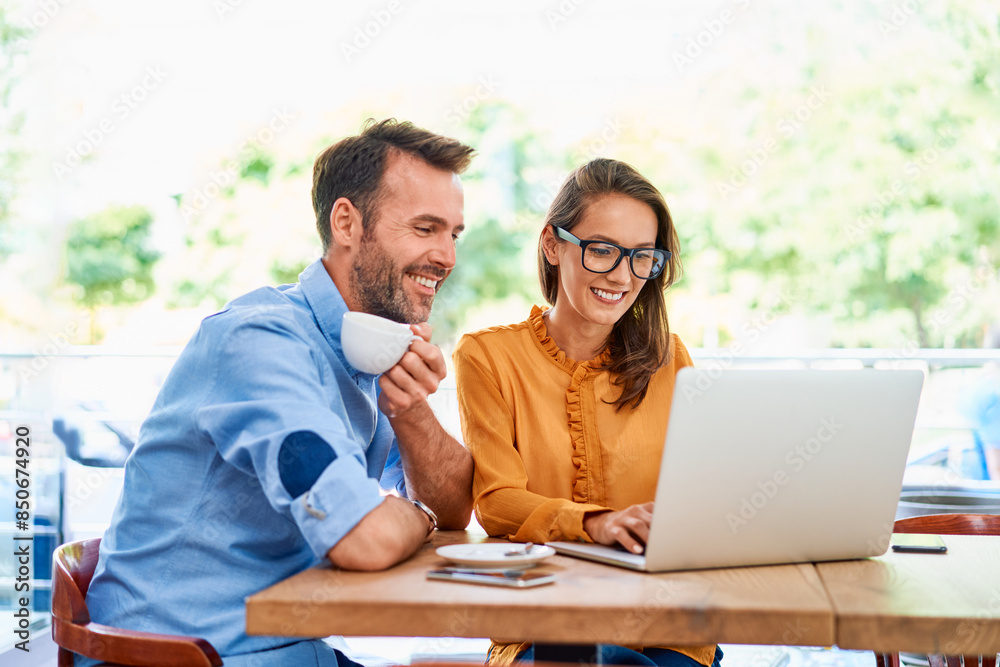 Two business people in a cafe using laptop together having coffee Two business people in a cafe using laptop together having coffee