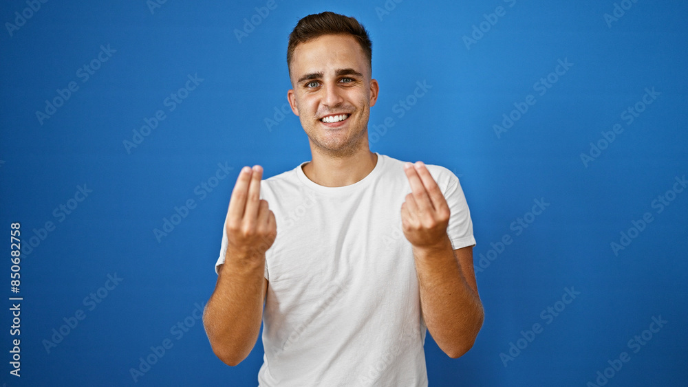 A cheerful young hispanic man wearing a white shirt gesturing with his hands isolated against a blue background. A cheerful young hispanic man wearing a white shirt gesturing with his hands isolated against a blue background.